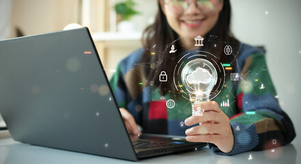 Woman holding light bulb with cloud icon. Digital technology concept, data sheet management with large database capacity and high security. Storage transition from computer to cloud computing.