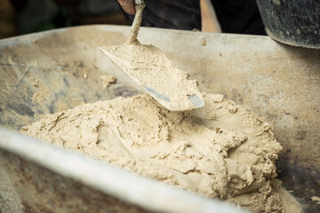 A worker applies a product to a stone wall with a trowel to begin construction.