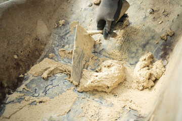 A laborer applies a product to a stone wall with a trowel to begin construction.