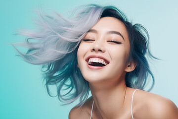 Laughing Asian woman with blue hair on pastel background
