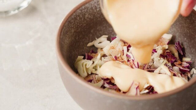 Chef cooking coleslaw, german Coleslaw salad made of freshly shredded white cabbage and grated carrot with homemade mayonnaise based salad dressing in wooden bowl.