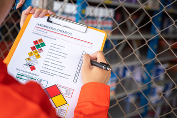 A worker is checking on the hazardous chemical material information form with background of...