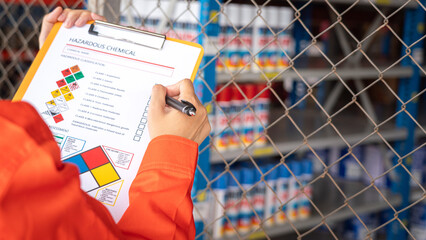 A worker is checking on the hazardous chemical material information form with background of...