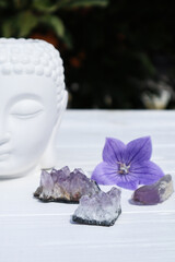 Amethyst stones near statue head of Buddha. Meditation place.