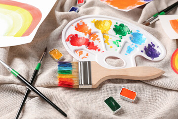 Artist's palette and brushes with paints on cloth background