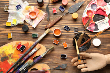 Artist's palettes with paints and brushes on brown wooden background
