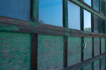 weathered peeling green paint old garage door in alley way with glass windows leading lines