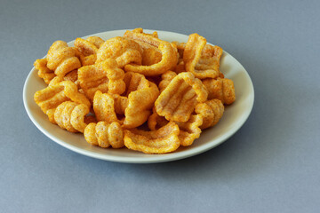 Ham flavored chips snacks on a plate on a gray background