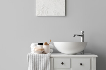 Sink bowl and bath accessories on table in light bathroom