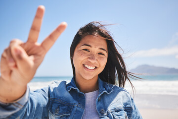 Portrait, woman and sign for peace on beach, holiday or profile picture from vacation in Indonesia on summer or break. Happy, face and smile at the ocean, sea or person travel in nature with freedom