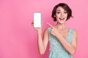 Naklejka premium Photo of young woman directing finger empty space smartphone touchscreen surprised website app store isolated on pink color background