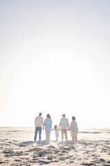 Love, travel and holding hands with big family on beach for vacation, bonding and summer. Freedom, care and relax with group of people walking at seaside holiday for generations, happiness and mockup