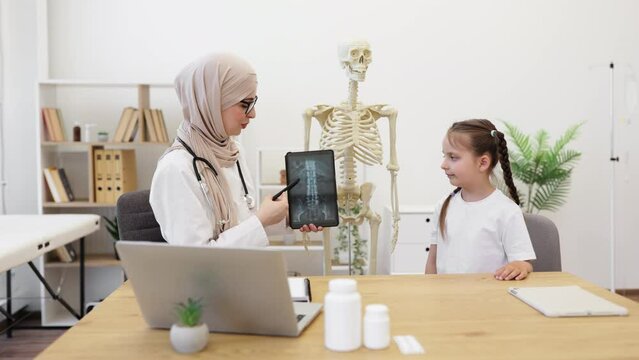 Girl looking at GP with CT scans on tablet in clinic office