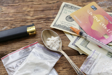 Drugs, syringe, money and lighter on wooden background