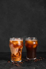 Glasses of tasty ice coffee with milk on black background