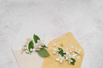 Composition with envelopes and beautiful jasmine flowers on light background