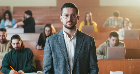 Portrait of handsome young Caucasian male professor at University wearing glasses and looking at...