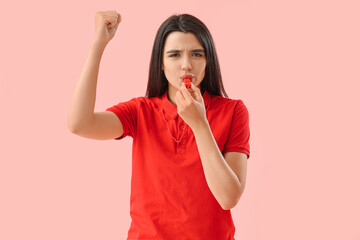 Female lifeguard whistling on pink background