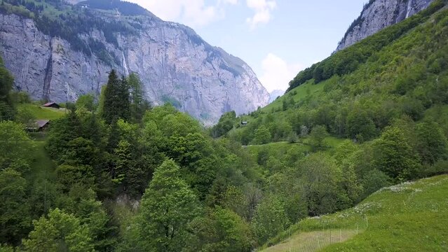 Drone takes off in famous Lauterbrunnen Valley in Switzerland with stunning cliffs, huge waterfall and peaceful nature.