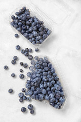 Plastic containers with fresh blueberry on white background