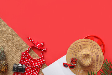 Bowl of strawberry with camera, pineapple and beach accessories on red background. Summer vacation concept