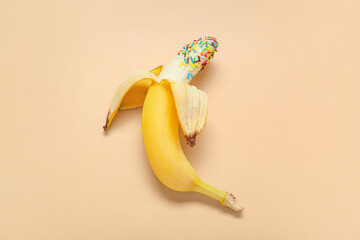 Fresh banana with sprinkles on beige background. Sex education concept