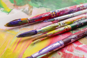 Dirty paint brushes on colorful background