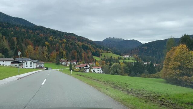 Road trip through Alps mountains in autumn. Point of view from inside car driving in Thiersee town on cloudy day