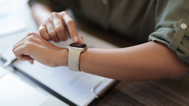 Close up business people using smartwatch at work.