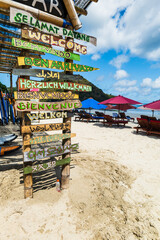 Fototapeta na wymiar Beach hut for surfers with welcome sign in many languages. Beach house signs for visitors in tropical beach resort