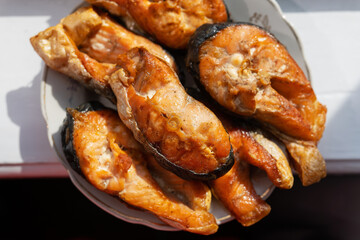Grilled salmon steaks lie on a plate, beautiful sunlight on the table. Delicious and healthy meal.