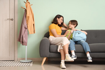 Mother sitting on sofa in hallway with her little son before school