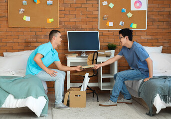 Male students unpacking things in dorm room on moving day