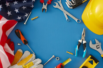 Engage your audience with a construction-themed Labor Day gathering. Top view photo of american flag, yellow hard hat, safety gloves, worker tools on blue background with empty space for ad or text