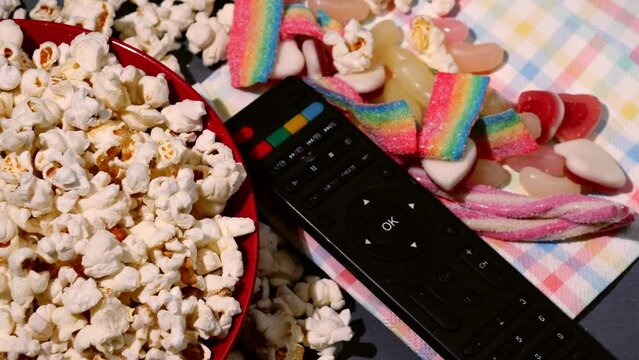 Television remote with popcorn and candy background