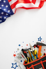 Join the celebration: Labor Day banner design. Top view vertical shot of USA flag, tools bag organizer, stars confetti on white background with empty space for advert or text
