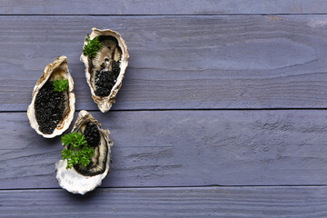Tasty oysters with black caviar on blue wooden background