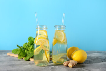 Bottles of tasty lemonade with ginger and mint on grey table