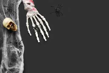 Skeleton hand, skull, web and spiders for Halloween celebration on dark background