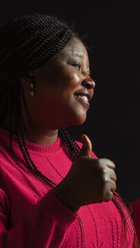 vertical video Side-view of lady with african american ethnicity showing thumbs up with a beautiful smile on her face. Against blank isolated background elegant black woman firmly gestures approval