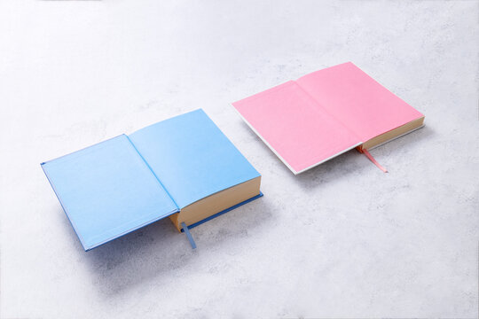 Two open blank books on whate table. Pink and blue first pages