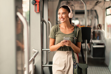 Passenger Woman Standing in Tram, Listening Music Online On Phone - obrazy, fototapety, plakaty