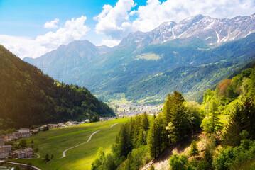 Small town in green summer valley surrounded by mountains in Swiss alps