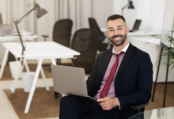 Fototapeta premium Glad confident attractive caucasian mature guy in suit use laptop, chatting and study
