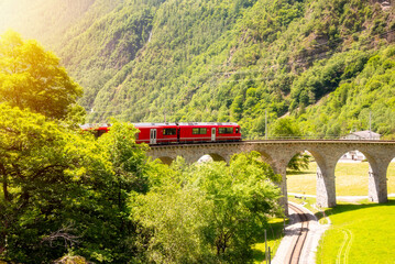 Fototapeta na wymiar Red train moving on vaiduct in summer in Switzerland