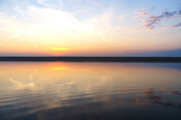 Reflection of the sunset in the water. Beautiful sunset over the sea. Colored sky at sunset.