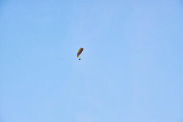 Paraglider silhouette flying in the blue sky.