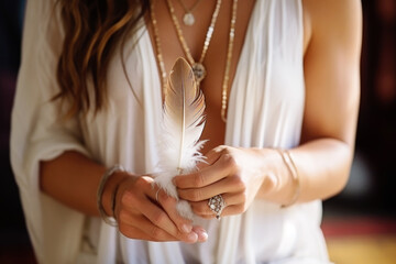 Woman with boho jewellery holding a feather in her hands close up