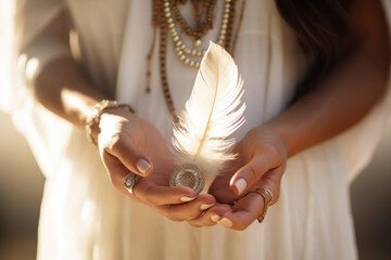 Woman with boho jewellery holding a feather in her hands close up