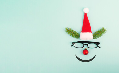 Face of a reindeer with a red bauble nose, fir antlers, a santa claus hat and eyeglasses, merry...
